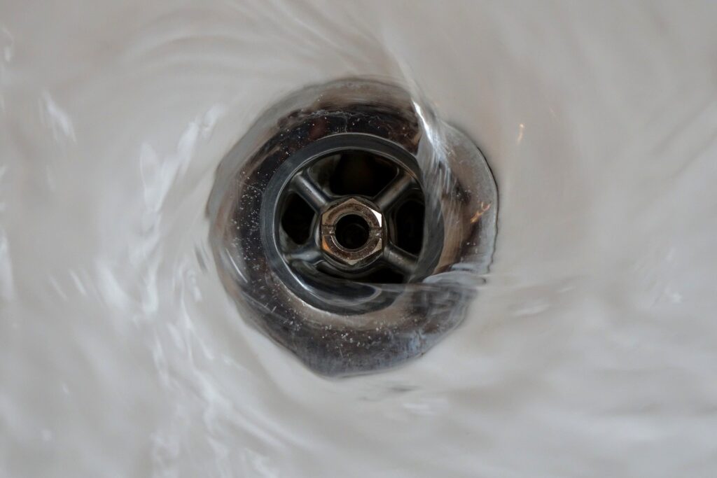 Close-up of water swirling down a metallic drain in a sink.
