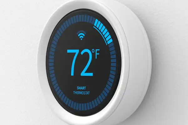A round smart thermostat mounted on a wall displays a temperature of 72°F with Wi-Fi connectivity indicated.